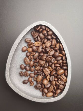 Roasted coffee beans in a ceramic bowl on a black background.の写真素材