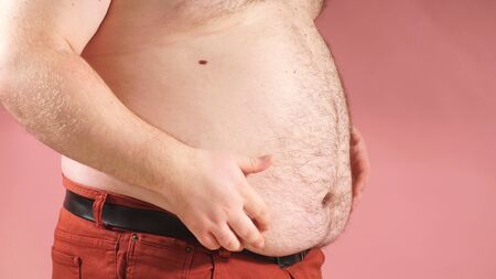 Man shows extra belly fat. Side view close-up.の写真素材