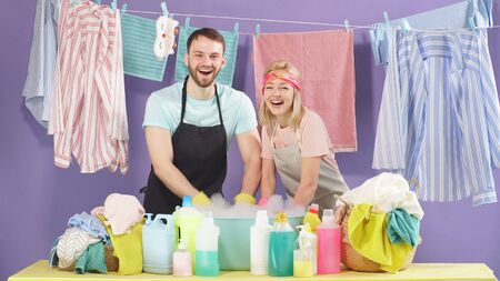 Cheerful smiling hard-working couple wash clothes that are recommended for hand washing. Washing clothes in the basin.の写真素材