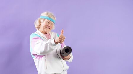 an Elderly lady with a yoga Mat on an isolated background. Old age and a healthy lifestyle.の写真素材