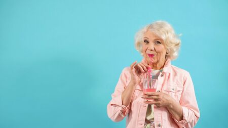 fashionable pensioner poses in a Studio with a cocktail in her hand on an isolated background.の写真素材