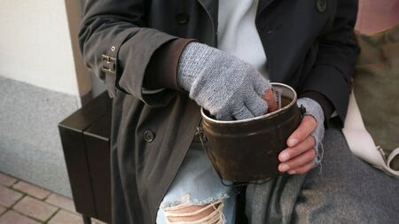 Male hands of a homeless old man holding a bowl, a glass for donations.の写真素材