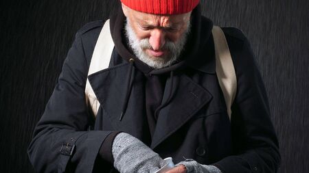 Homeless old man, beggar, bearded man counting coins to eat and drink, isolated background.の写真素材