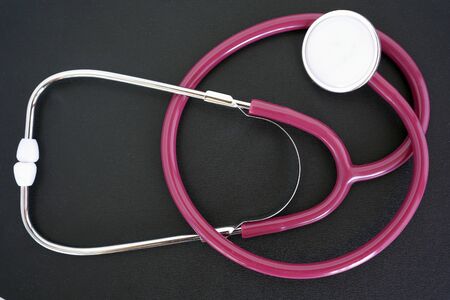 Maroon stethoscope, phonendoscope for the doctor, for the diagnosis of lung disease, on an isolated background. Stethoscope, phonendoscope isolated on a black background.の写真素材
