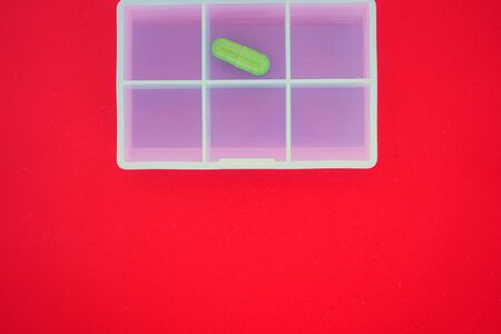Plastic medicine diary with two capsules, box with one capsules for tablets top view. red...