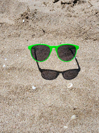 green sunglasses on a sandy beach on a Sunny day.の写真素材