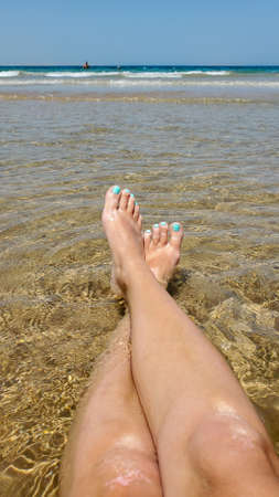 womens feet on the golden sand in the sea, a photo with a view from aboveの写真素材