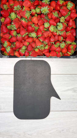 Plastic box full of ripe fragrant strawberries. Ripe large strawberries with green leaves. Top view. Close-up.の写真素材
