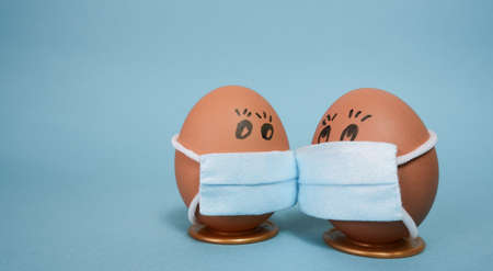Easter eggs with virus protection concepts. Easter eggs in a mask to decorate the Easter holidays. On a blue background with copyspace.の写真素材
