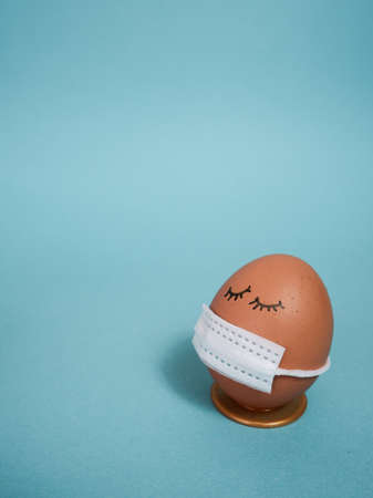 Easter eggs with virus protection concepts. Easter eggs in a mask to decorate the Easter holidays. On a blue background with copyspace.の写真素材
