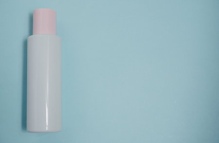 White plastic mock-up of a bottle of cosmetic lotion, peeling, cream with a pink cap on a blue...