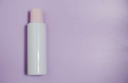 White plastic mock-up of a bottle of cosmetic lotion, peeling, cream with a pink cap on a blue background. Top view with a copy of the text space on the right.の写真素材