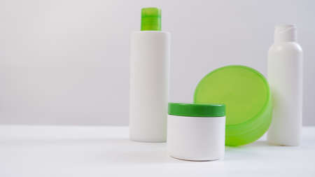 Empty bottles and tubes with disc press cap for branding and mockup. White empty bottle with green bottle cap, space for text on the left.の写真素材