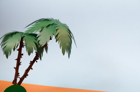 Two palm trees on a sandy island under the sun in the sea with paper waves.の写真素材