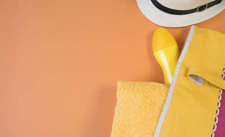 Beach flat lay accessories. Sun hat, yellow towel, yellow cream bottle, sun protection bottle, and...