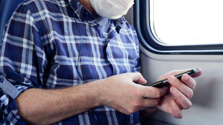 Close-up of a man in a blue plaid shirt sitting on the subway, listening to music on headphones and...