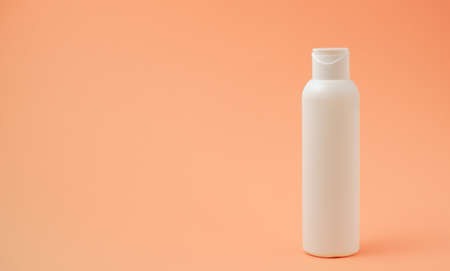 White pure suntan lotion, body cream, shampoo or sunscreen bottle for packaging mockup. White bottle and orange background. Minimal summer skincare and sun protection concept. Place for your text.の写真素材