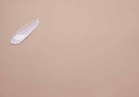 Creamy texture. A smear of white hand cream on a beige background.の写真素材