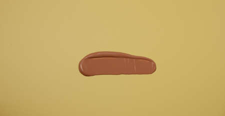 Makeup product smear on yellow background. view from above.