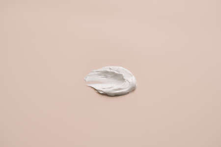 The texture of white delicate cream on a beige background.