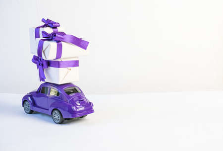Volgograd, Russia - October 15, 2021: Gift boxes on a toy purple car on a white backgroundのeditorial素材