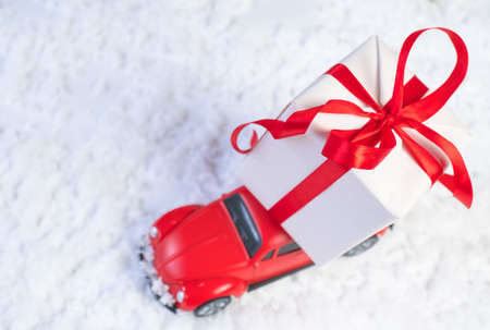 Volgograd, Russia - October 15, 2021: Red retro toy car delivering Christmas or New Year gifts on the roof against a snowy white backgroundのeditorial素材