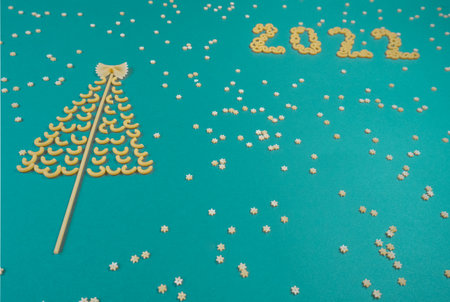 Christmas tree lined with dry pasta and numbers 2022 and stars from pasta on a green paper...