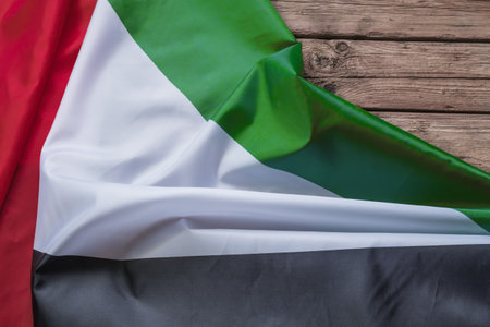 The flag of the United Arab Emirates lies on a brown wooden background with space for text or imageの写真素材