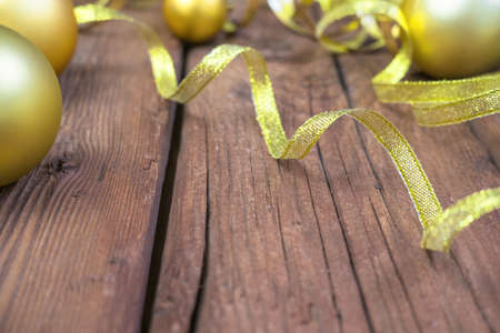 Christmas composition of yellow Christmas balls, fir branches, and a gold ribbon on a brown wooden backgroundの写真素材