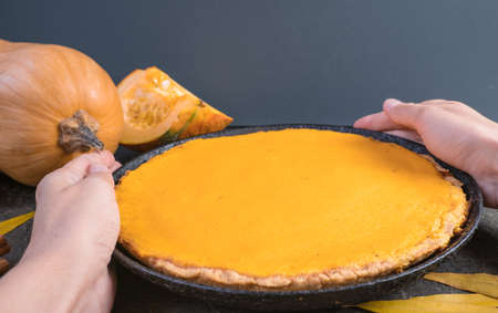 Traditional autumn dishes. Halloween, Thanksgiving. Spicy American Pumpkin Pie, on black with gold stone table.の写真素材