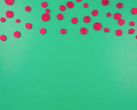 Green background with red glittering confetti with space for text. Happy new year