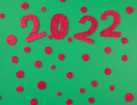 happy new year 2022 background new year holiday card. Shiny red numbers and candies on a green...
