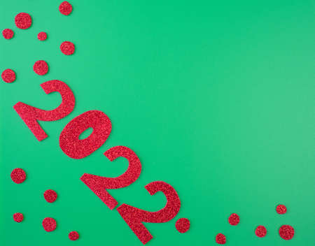happy new year 2022 background new year holiday card. Shiny red numbers and candies on a green backgroundの写真素材
