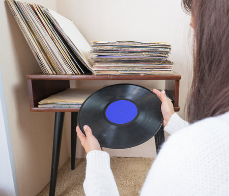 Woman choosing vinyl records at home for listening.の写真素材