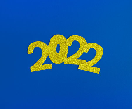 golden glittering shapes of numbers 2022 in the center on a bright blue background, minimalism new...