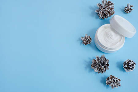 Jar of cream for hands, eyes, face, and fir cones on a blue background. Set of cosmetics for skin and body care with pine needlesの写真素材