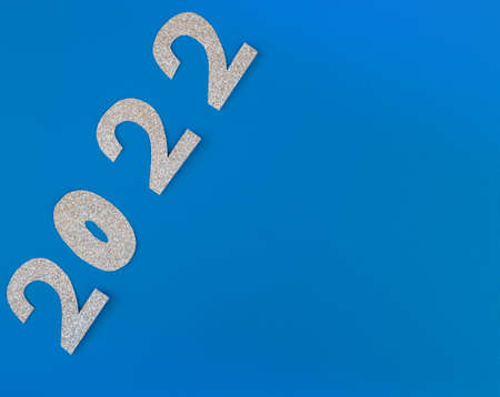 silver glitter shapes of numbers 2022 on blue background, minimalism new year concept. Place for...