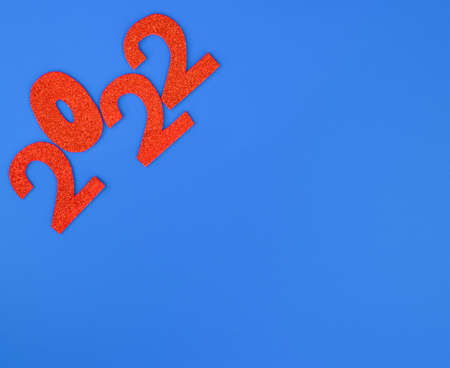 Happy New Year 2022. Christmas background with red glittering numbers 2022 close-up on blue background. View from above. Place for your text.の写真素材