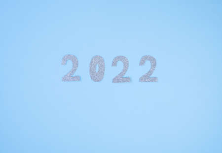 Happy New Year 2022. Christmas background with silver glittering numbers 2022 on light blue...