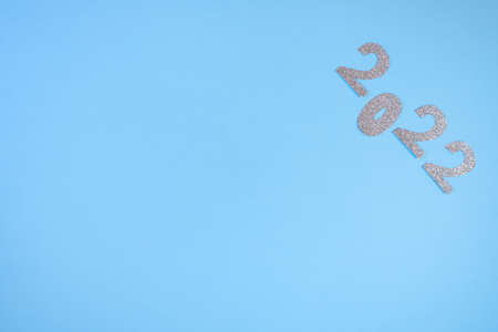 Happy New Year 2022. Christmas background with silver glittering numbers 2022 on light blue...