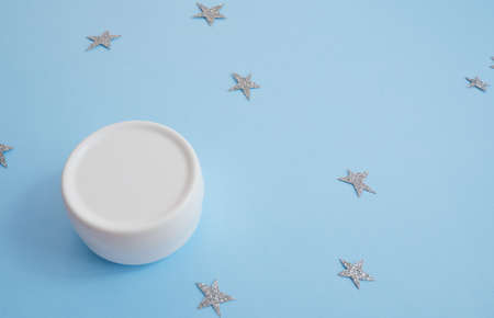 White matte cream jar with plastic lid on blue background with starsの写真素材