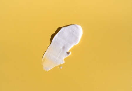 White smear of cosmetic cream on a yellow background. Creamy base texture isolated. A smear of face cream. Close-up of creamy texture.の写真素材