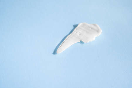 White smear of cosmetic cream on a blue background. Creamy base texture isolated. A smear of face...
