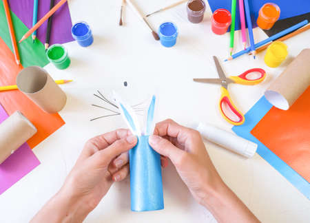 step 3. DIY paper rabbit from a roll of toilet paper. Easy craft for kids on white background,...