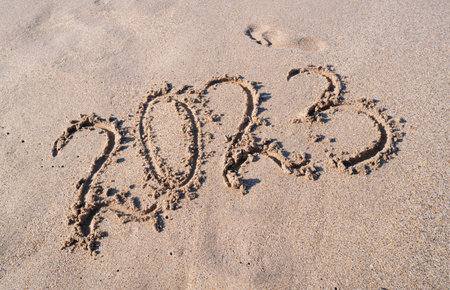 New year 2023. Figures on the sandy seashore.