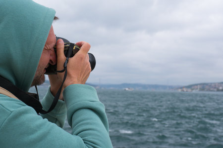 A male tourist photographs the landscape on the Bosphorus embankment in Istanbul, Turkey, as a keepsakeの写真素材