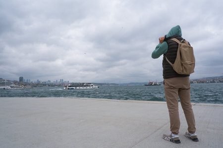 A male tourist photographs the landscape on the Bosphorus embankment in Istanbul, Turkey, as a keepsakeの写真素材