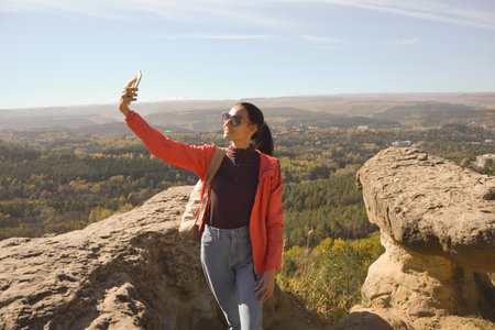 Young beautiful woman traveler taking selfie portrait on mountain top - Happy smiling girl using...