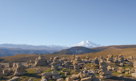 Mountain Elbrus. Autumn Elbrus. Autumn in the Caucasus mountains. Gilli-Suu district. Landscape of snow-capped mountains through stone pyramids. Snowy peaks. Panorama of Elbrusの写真素材