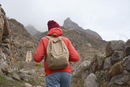 A free woman traveler walks along paths in the mountains on a foggy autumn day. Adventure travel and...